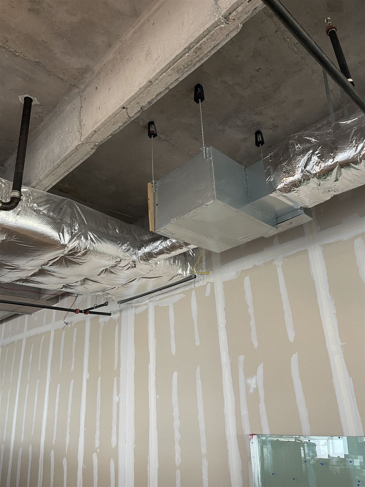 Ceiling-hung fan coil unit with insulated ductwork installed in a commercial buildout