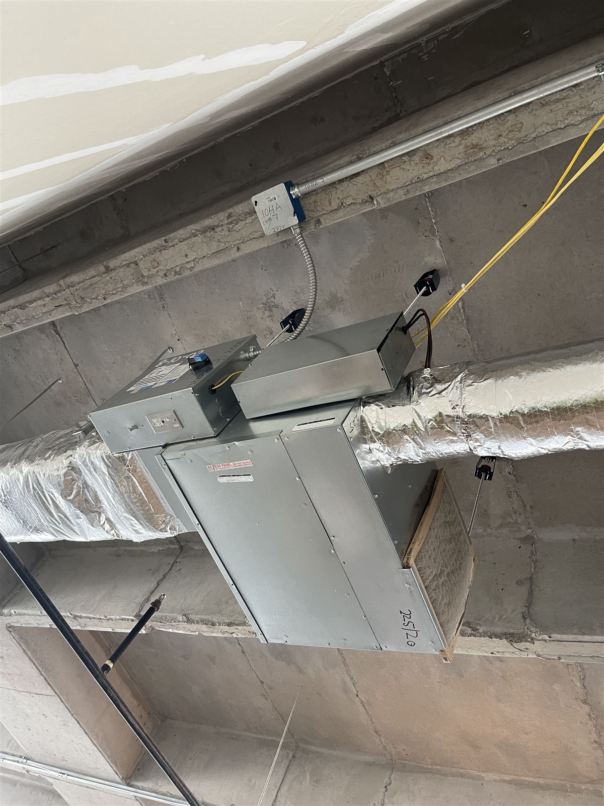 Fan coil unit and labeled electrical rough-in during a commercial mechanical installation