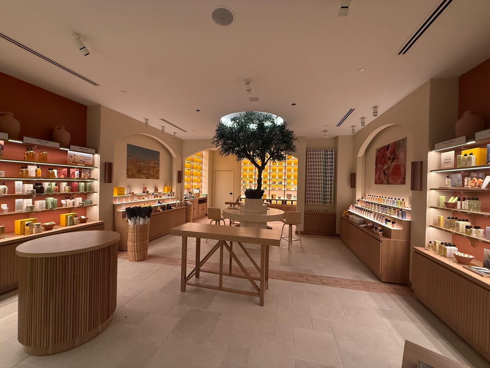 Finished L'Occitane en Provence store at Southlake Town Square with olive-tree centerpiece, backlit shelving, and lighting installed by Phanton Mechanical