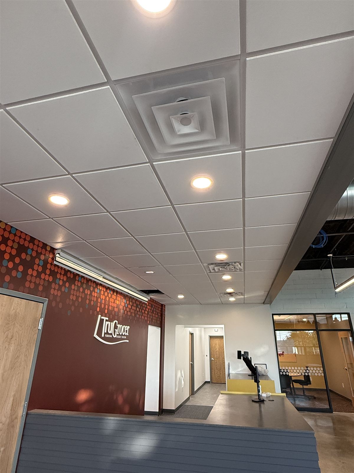 Finished ceiling with recessed lighting and HVAC diffusers above the TruGrocer member lobby