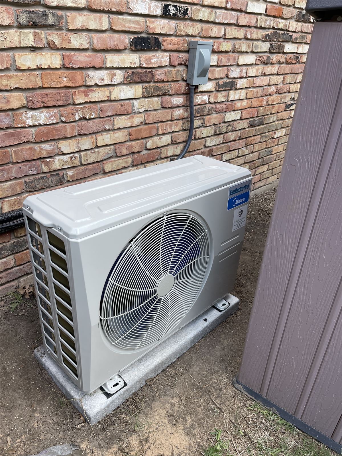 Side-discharge heat pump condenser installed on a pad beside a DFW residence